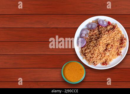 Schezwan Chicken Gebratener Reis auf einem Teller mit Hühnercripri in einer Schüssel auf einem Holztisch. Speicherplatz kopieren. Stockfoto