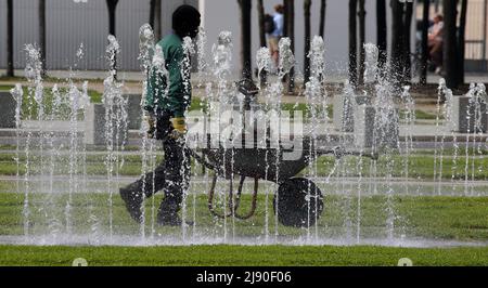 Berlin, Deutschland. 19.. Mai 2022. Ein Mitarbeiter des Zentralgartenamtes schiebt seine Schubkarre bei Temperaturen um 30 Grad Celsius an einem Brunnen vor dem Bundeskanzleramt vorbei. Quelle: Wolfgang Kumm/dpa/Alamy Live News Stockfoto