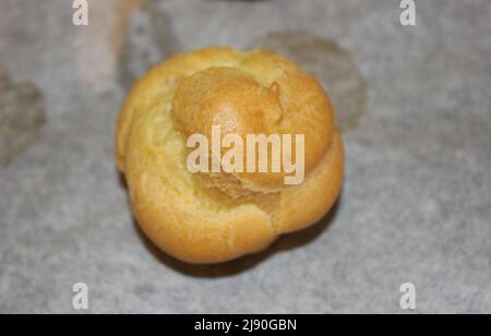 Nahaufnahme eines schönen frisch gebackenen Cremepuffs, perfekt golden noch auf dem Pergamentpapier Stockfoto