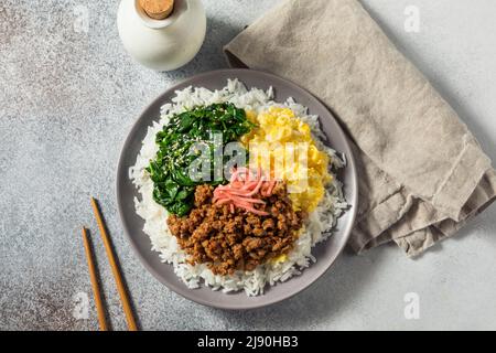 Hausgemachte japanische Sanshoku Don Chicken Rizschüssel mit Ei und Spinat Stockfoto