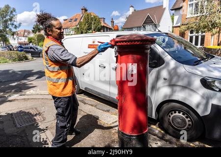 Royal Mail Postarbeiter, der einem Briefkasten einen roten Anstrich gibt, London, England, Großbritannien Stockfoto