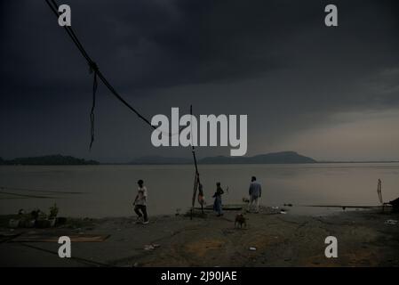 Guwahati, Indien. 19.. Mai 2022. Am 19. Mai 2022 versammeln sich in Guwahati die Einheimischen am Ufer des Flusses Brahmaputra, während sich dunkle Wolken am Himmel versammeln. Quelle: David Talukdar/Alamy Live News Stockfoto