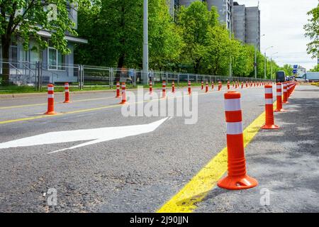 Orangefarbene Stangen auf der Straße. Auf der Straße werden Kunststoffstangen zur Teilung von Fahrspuren aufgestellt Stockfoto