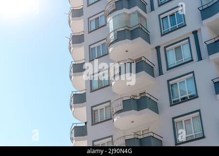 Lichteffekte von Sonnenstrahlen auf Stadtgebäude. Fragment einer modernen Wohnwohnung mit Balkonen. Stockfoto