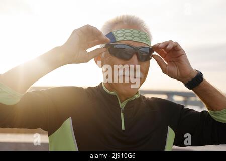 Horizontale Brustkorb Portraitfotos der positiven älterer Mann mit Sonnenbrille während Morgen Workout Stockfoto