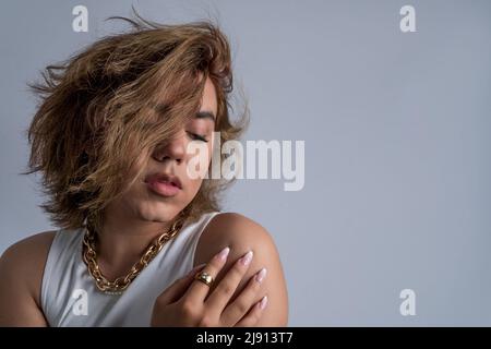 Portrait von nicht-binären Jungen mit langen Haaren und coolem Stil mit ruhiger Haltung im Studio Stockfoto