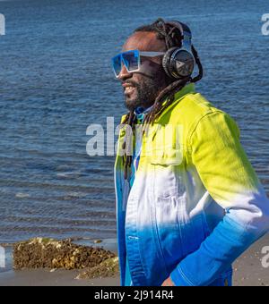 Hübscher attraktiver junger afroamerikanischer Mann mit Dreadlocks, der im Freien Musik hört. Straßenfoto. White Rock BC, Kanada, März 3,2022 Stockfoto