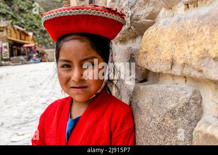 Ein Indigenes Mädchen In Traditioneller Tracht Vor Der Archäologischen Stätte Ollantaytambo, Ollantaytambo, Dem Heiligen Tal, Cusco Region, Peru. Stockfoto