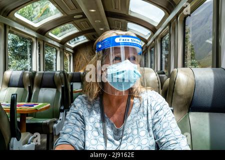 Eine reife Frau an Bord eines leeren Perurail-Zuges, die während der Pandemie von Covid 19 in Peru zwischen den Bahnhöfen Ollantaytambo und Aguas Calientes pendeln. Stockfoto