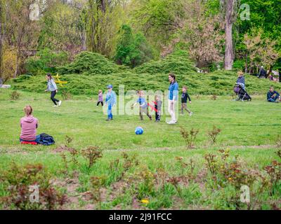Bukarest, Rumänien - 04.15.2022: Menschen, die sich im Park von König Mihai I (Herestrau) in Bukarest entspannen und Spaß auf dem Rasen haben Stockfoto