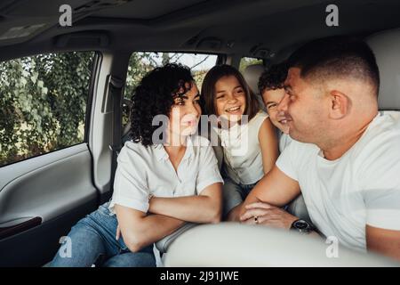 Mutter und Vater mit zwei Teenagekindern auf Wochenend-Roadtrip, Happy Four Mitglieder Familie auf Reisen mit dem Minivan Auto Stockfoto