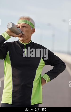 Kaukasische älterer Mann Trinkwasser während der morgendlichen Workout horizontale mittellange Aufnahme Stockfoto