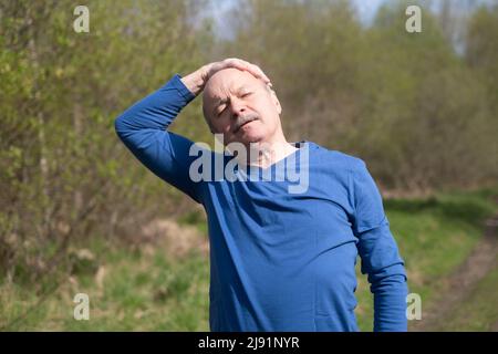 Senior Läuferin mit Armband macht Dehnungsübungen. Frühling Natur. Gesunde Lebensweise im Alter. Stockfoto