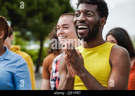 Multiethnische Vielfalt feiert gemeinsam im Freien bei PRIDE-Veranstaltung - Fokus auf schwulen afrikanischen Mann mit Make-up Stockfoto