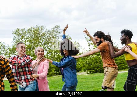 Multiethnische Gruppe von verschiedenen Freunden, die Spaß haben, gemeinsam im Freien während der Sommerferien zu tanzen - Fokus auf Mann mit Beinprothese Stockfoto