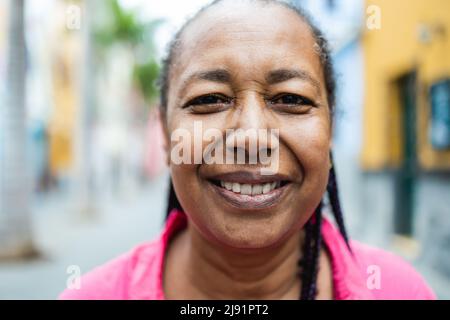 Glückliche afrikanische ältere Frau posiert und lächelt vor der Kamera im Freien - Senioren Lifestyle-Konzept Stockfoto