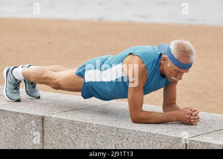 Good-looking Strong älterer Mann tun plank Übung auf Strand, horizontale full Shot Stockfoto