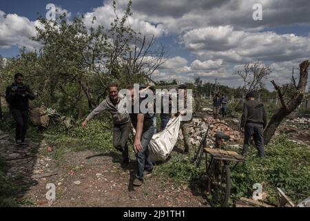 Malaya Rohan, Ukraine. 19.. Mai 2022. Am Donnerstag, den 19. Mai 2022, schleppen Männer den Leichnam eines toten russischen Soldaten, von dem aus er in einem Hinterhof einer Person in Mala Rohan, Ukraine, begraben wurde. Mala Rohan ist ein kleines Dorf, das von den ukrainischen Truppen nach dem Angriff Russlands auf die Ukraine zurückgenommen wurde. REDAKTEURE NOTIEREN DEN INHALT. Foto von Ken Cedeno/UPI Credit: UPI/Alamy Live News Stockfoto