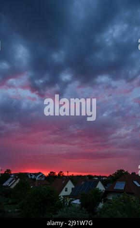 Leipzig, Deutschland. 19.. Mai 2022. Die untergehende Sonne erhellt die aufziehenden Gewitterwolken über dem westlichen Leipzig. Die Menschen in Sachsen, Sachsen-Anhalt und Thüringen müssen sich in den nächsten zwei Tagen auf heftige Gewitter einstellen, am Freitag sogar auf extreme Gewitter. Quelle: Jan Woitas/dpa/Alamy Live News Stockfoto