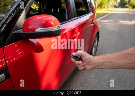 Frauen drücken die Hand auf die ferngesteuerten Alarmanlagen des Autos Stockfoto