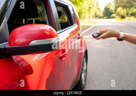 Frauen drücken die Hand auf die ferngesteuerten Alarmanlagen des Autos Stockfoto