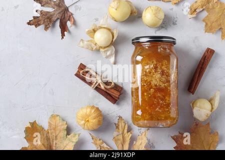 Hausgemachte transparente Physalis-Marmelade mit Zimt im Glas auf hellgrauem Hintergrund, Draufsicht Stockfoto