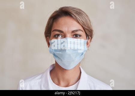 Horizontales Nahaufnahme-Porträt einer modernen jungen erwachsenen Ärztin mit Schutzmaske und Blick auf die Kamera Stockfoto