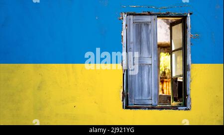 Kaputtes Fenster auf einer Ukraine Flagge farbigen Wand . Stockfoto