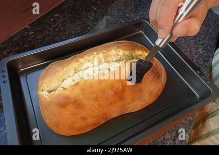 Schwäbische Küche, Zubereitung Ulmer Zuckerbrot, süßer Hefe Hefeteig mit Fenchelsamen, gebacken, Brot mit Rosenwasser aufstreuen, Bürste Stockfoto