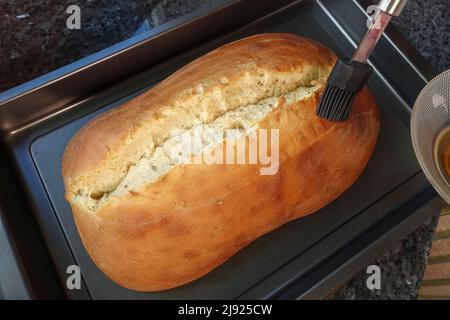 Schwäbische Küche, Zubereitung Ulmer Zuckerbrot, süßer Hefe Hefeteig mit Fenchelsamen, gebacken, Brot mit Rosenwasser aufstreuen, Bürste Stockfoto