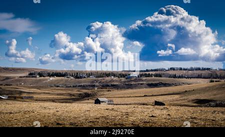 Eine Farmszene mit alten Getreidehüllen und entfernten Grundstücken auf sanften Hügeln in Rocky View County Alberta Canada unter einem dramatischen Himmel. Stockfoto