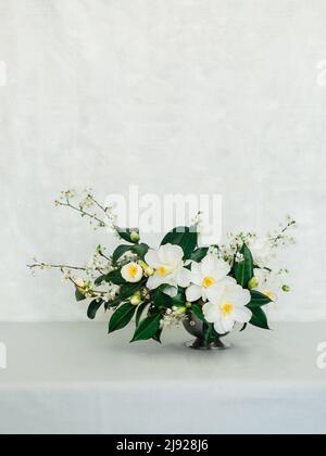 Hochzeitsblumen auf einer grauen Tischdecke an einer weißen Wand Stockfoto