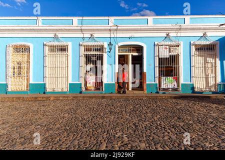 Kubaner vor dem Geschäft, gepflasterte Straße, Kolonialhaus mit typischen verbarrten Fenstern und Türen, Bars, gesperrt, Altstadt, Trinidad, UNESCO-Welt Stockfoto