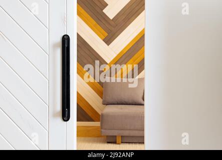 Geöffnete Schiebetür in einem Raum mit farbenfroher Holzwand. Stilvolles, modernes Apartment-Design Stockfoto