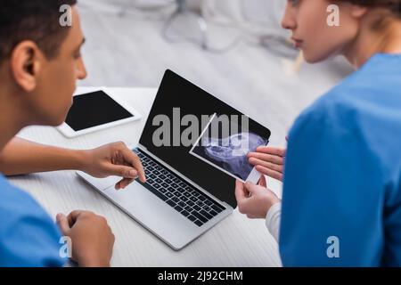 Verschwommene multiethnische Tierärzte, die in der Klinik mit Ultraschalluntersuchungen von Tieren arbeiten Stockfoto