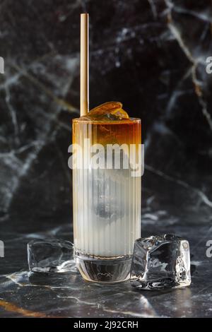 Dunkler und stürmischer Cocktail, der auf dem schwarzen Marmorhintergrund steht. Erfrischender alkoholiger Rum Dunkler und stürmischer Cocktail mit Ingwer-Bier Stockfoto