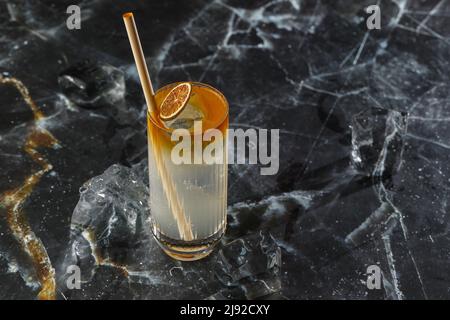 Dunkler und stürmischer Cocktail, der auf dem schwarzen Marmorhintergrund steht. Erfrischender alkoholiger Rum Dunkler und stürmischer Cocktail mit Ingwer-Bier Stockfoto