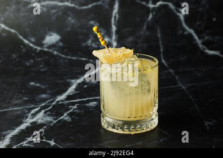 Alkoholischer Scotch Whiskey Penicillin Drink Cocktail mit Zitrone, Honigsirup und kandiertem Ingwer. Cocktailglas auf schwarzem Hintergrund. Stockfoto