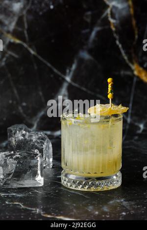 Alkoholischer Scotch Whiskey Penicillin Drink Cocktail mit Zitrone, Honigsirup und kandiertem Ingwer. Cocktailglas auf schwarzem Hintergrund. Stockfoto