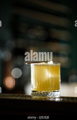 Fruchtmixologie mit Mezcal und trockenem Kalk auf schwarzem Marmorboden. Cocktails in warmen Farben. Mezcal-Cocktail Stockfoto