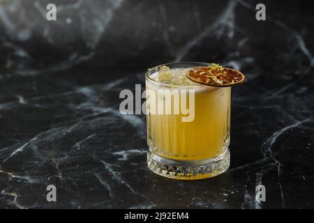 Fruchtmixologie mit Mezcal und trockenem Kalk auf schwarzem Marmorboden. Cocktails in warmen Farben. Mezcal-Cocktail Stockfoto