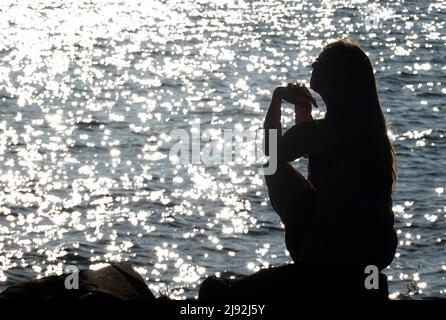 29.07.2021, Bolsena, Viterbo, Italien - Silhouette: Frau beim Sonnenbaden am Ufer des Bolsena-Sees. 00S210729D578CAROEX.JPG [MODELLVERSION: NEIN, EIGENTUM Stockfoto
