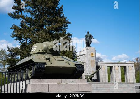 26.04.2022, Berlin, , Deutschland - Europa - Ein T-34 Panzer an der sowjetischen Gedenkstätte mit der Statue des Soldaten der Roten Armee entlang der Straße des 17. Juni in Stockfoto