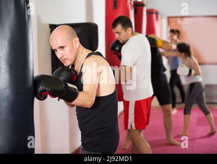 Ein junger Mann schlägt einen Boxsack Stockfoto