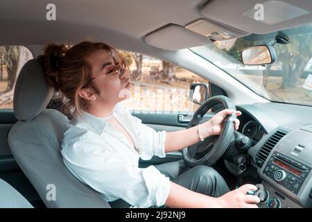 Nicht binäre Jugendliche fahren ein Auto mit der Hand auf dem Hebel in den Rückspiegel schauen. Hochwertige Fotos Stockfoto