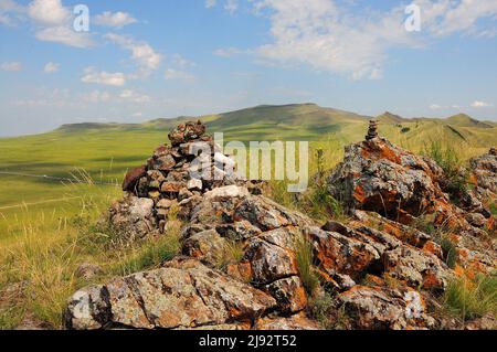 Rituelle Steinpyramiden auf einem Berg mit Blick auf die endlose hügelige Steppe. Chakassien, Sibirien, Russland. Stockfoto