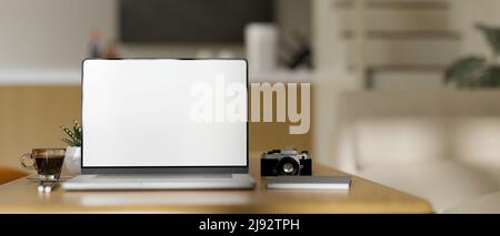 Home-Arbeitsplatz mit Zubehör und Laptop-Computer White-Screen-Mockup auf Holzschreibtisch über verschwommene moderne minimal Schlafzimmer im Hintergrund. Nahaufnahme Stockfoto