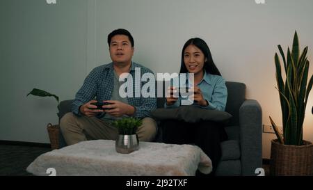 Asiatische Paare haben Spaß spielen in ihrem Wohnzimmer in der Nacht. Stockfoto