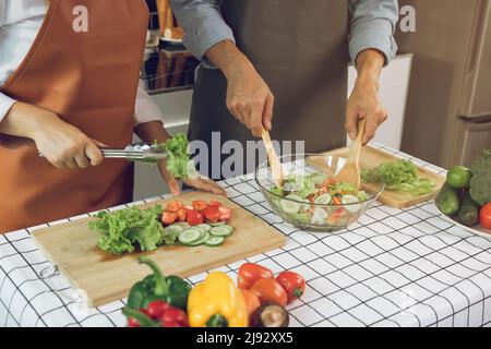 Asiatisches Paar genießt Kochen Gemüsesalat in der Küche. Stockfoto