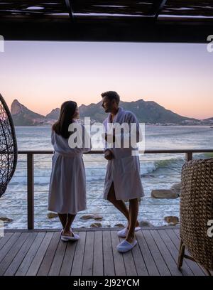 Ein Paar Männer und Frauen trinken Kaffee während des Sonnenaufgangs auf dem Balkon im Urlaub in Kapstadt Südafrika. Stockfoto